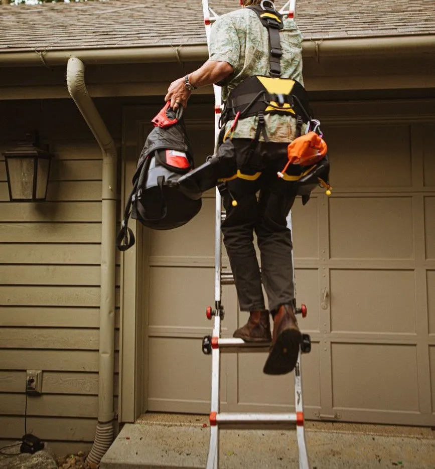 A Clearrun fitter in a safety harness climbing a ladder to the gutter of a house