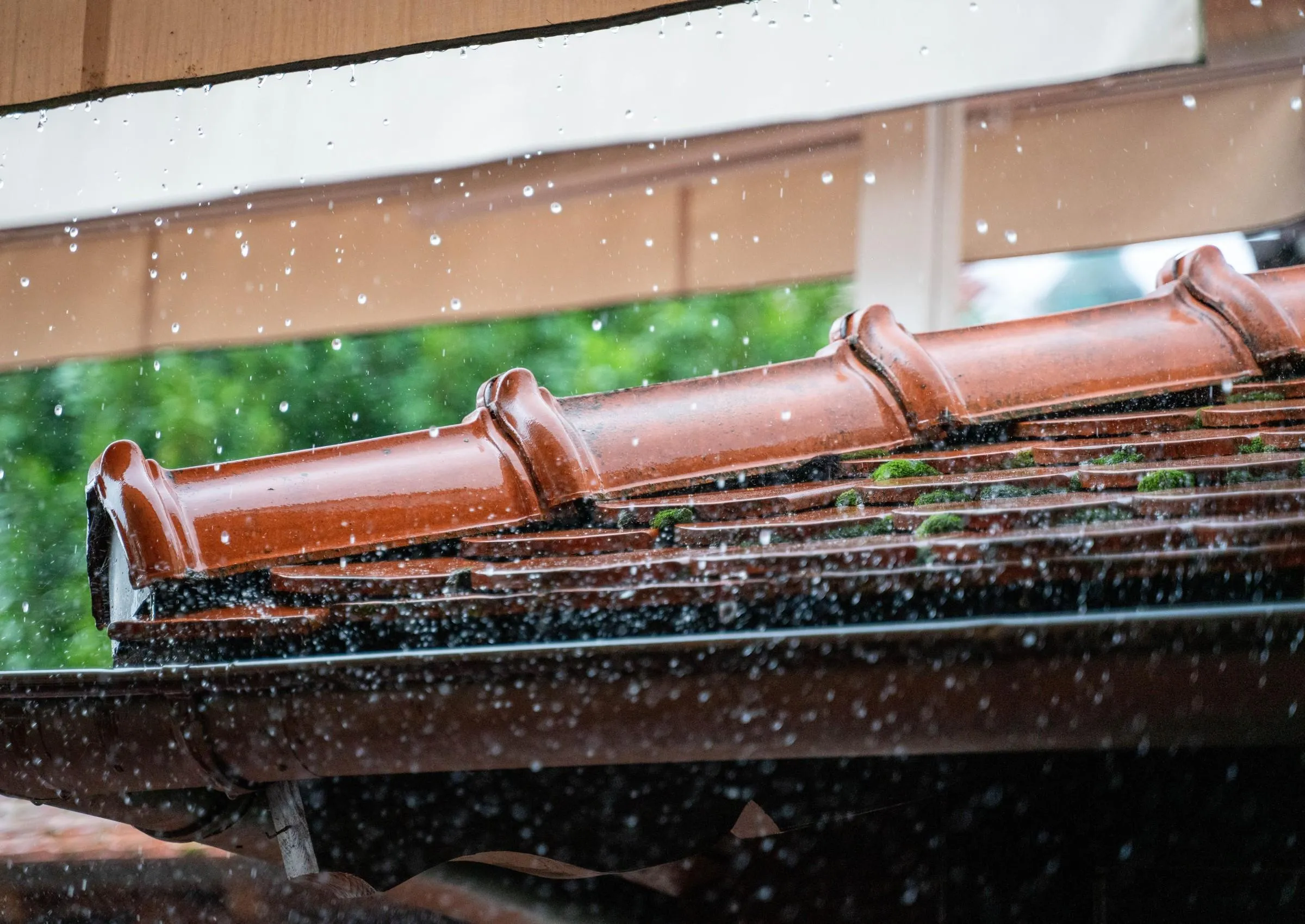 Rain bouncing off wet clay roof tiles into a dark gutter below