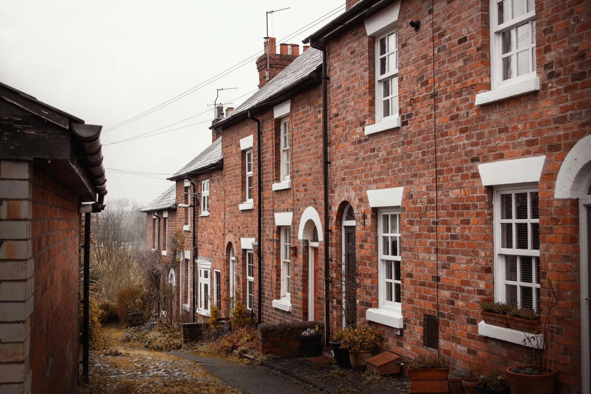 A row of red-brick terraced houses with black gutters and downpipes on a grey day